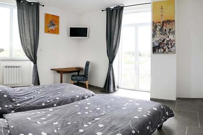 Maison en pierre avec toit en ardoise, entourée d'arbres et de végétation, sous un ciel partiellement nuageux.