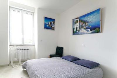 Maison en pierre avec toit en ardoise, entourée d'arbres et de végétation, sous un ciel partiellement nuageux.