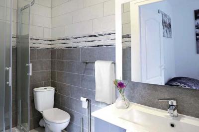 Maison en pierre avec toit en ardoise, entourée d'arbres et de végétation, sous un ciel partiellement nuageux.