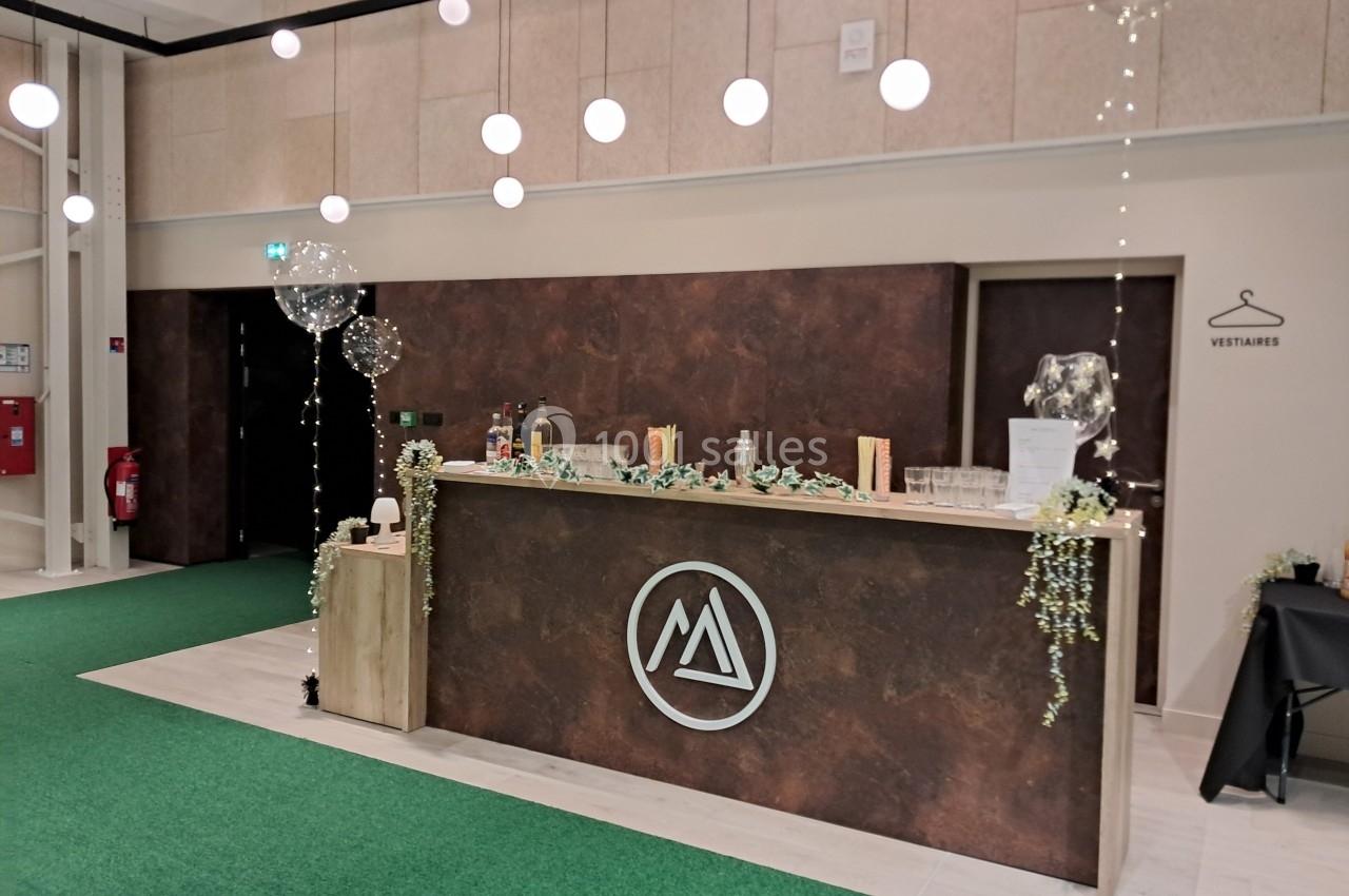 Comptoir de réception décoré avec des guirlandes lumineuses et des ballons, situé dans un espace intérieur moderne.