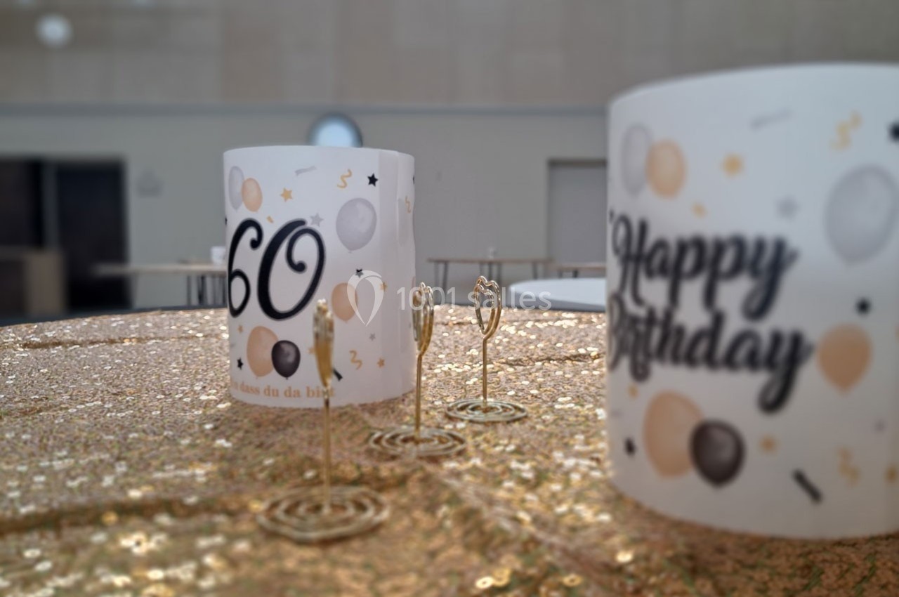 Décoration d'anniversaire avec bougies dorées et gobelets ornés de motifs festifs et du chiffre 60.