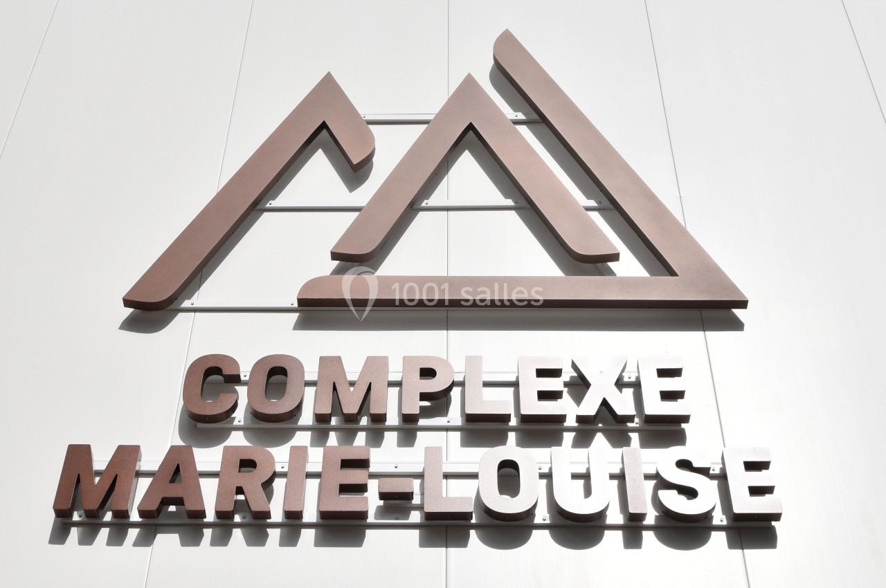 Façade blanche avec le logo et le nom ’Complexe Marie-Louise’ en lettres métalliques sous un ciel bleu.