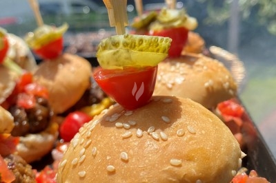Camion-restaurant jaune décoré de plantes et guirlandes lumineuses, proposant pâtes, gnocchis et cocktails.