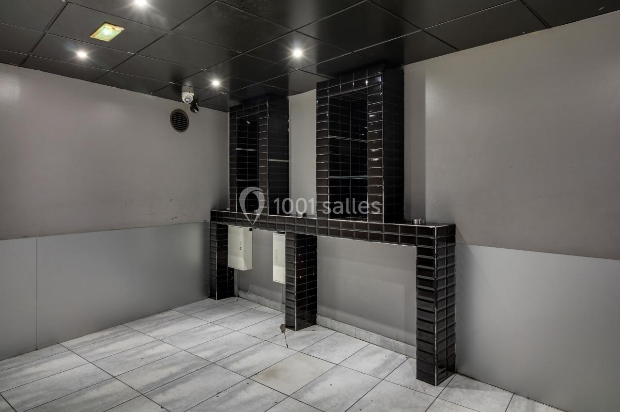 Salle de bain moderne avec murs gris, carrelage au sol clair et deux lavabos encastrés dans un meuble noir.