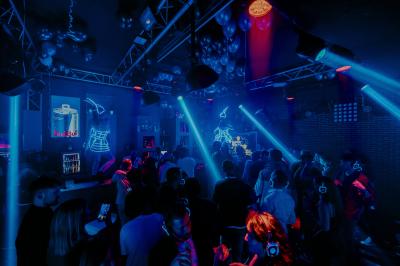 Personnes dansant avec des casques audio dans une ambiance de lumière bleue et rose lors d'une soirée silencieuse.