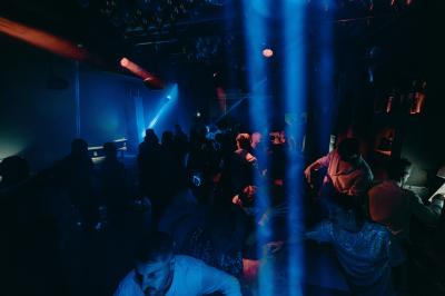 Personnes dansant avec des casques audio dans une ambiance de lumière bleue et rose lors d'une soirée silencieuse.