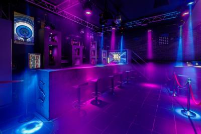 Personnes dans une discothèque sombre participant à une soirée silencieuse avec des casques audio lumineux.