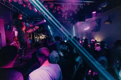 Personnes dans une discothèque sombre participant à une soirée silencieuse avec des casques audio lumineux.