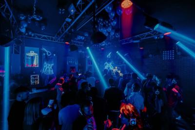 Personnes dans une discothèque sombre participant à une soirée silencieuse avec des casques audio lumineux.