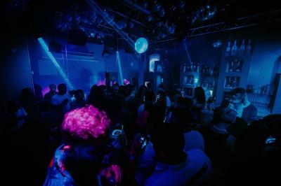 Personnes dans une discothèque sombre participant à une soirée silencieuse avec des casques audio lumineux.