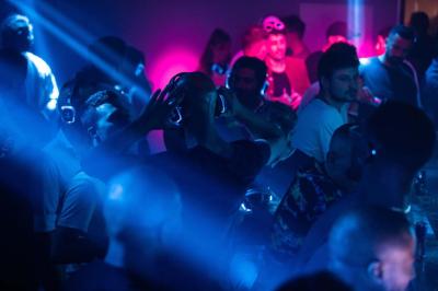 Personnes dans une discothèque sombre participant à une soirée silencieuse avec des casques audio lumineux.