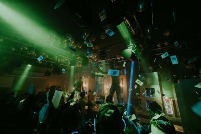 Personnes dans une discothèque sombre participant à une soirée silencieuse avec des casques audio lumineux.