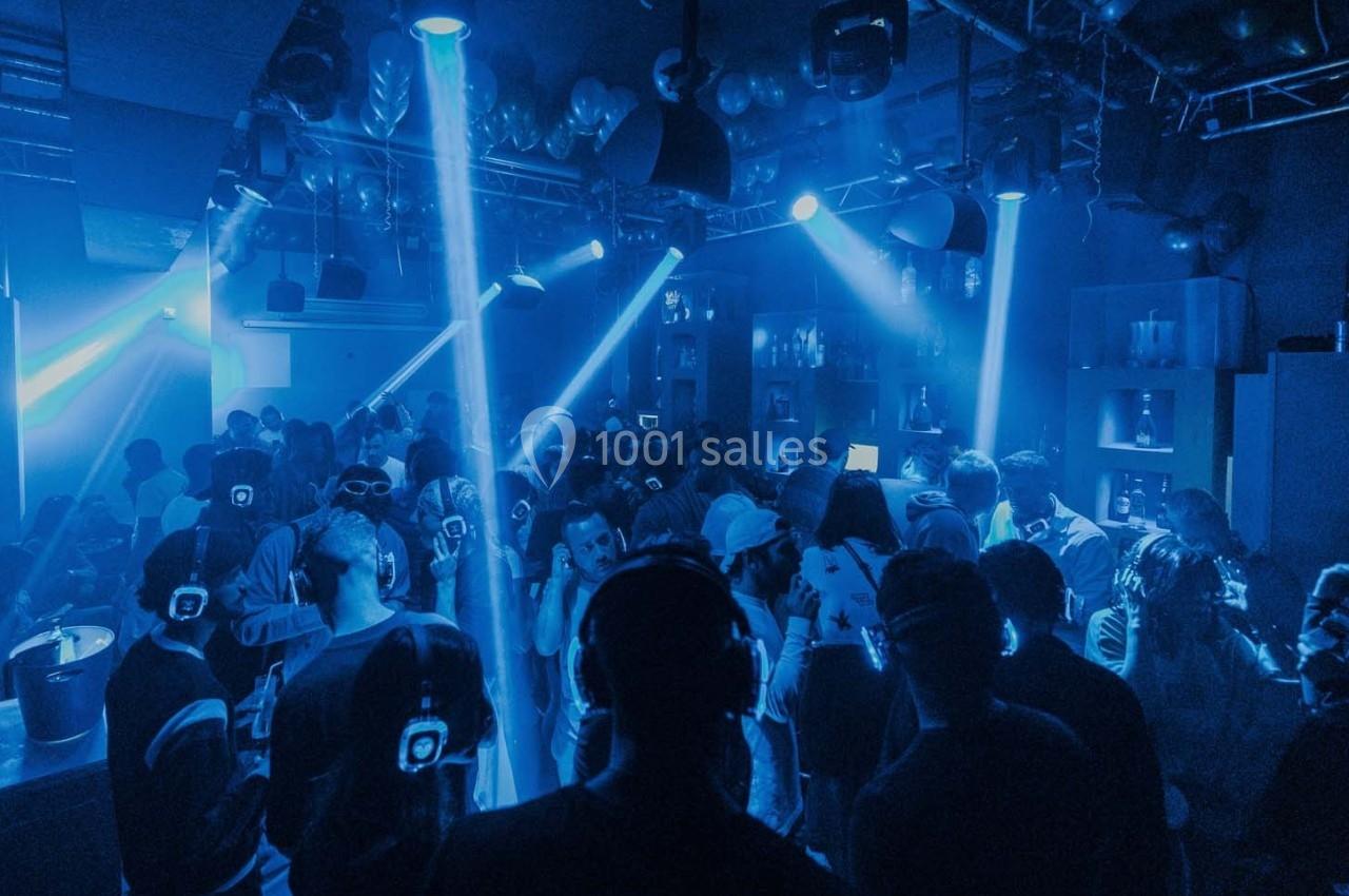 Personnes dans une discothèque sombre participant à une soirée silencieuse avec des casques audio lumineux.