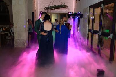 Un couple danse sur une piste extérieure éclairée, entouré de bulles, avec un DJ en arrière-plan.