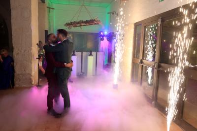 Un couple danse sur une piste extérieure éclairée, entouré de bulles, avec un DJ en arrière-plan.