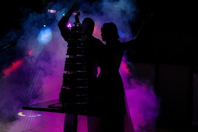 Un couple danse sur une piste extérieure éclairée, entouré de bulles, avec un DJ en arrière-plan.