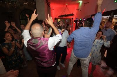Des personnes dansent et célèbrent dans une salle éclairée, avec des lumières colorées et une ambiance festive.