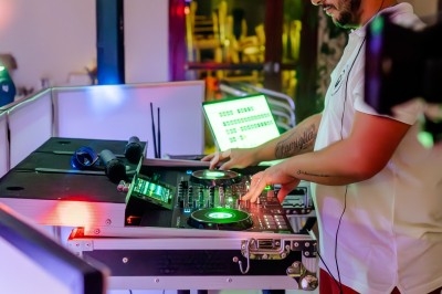 Un DJ mixe de la musique sur une console dans un environnement éclairé par des lumières colorées.