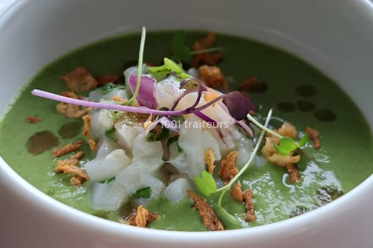 Bol de soupe verte garnie de morceaux de poisson cru, pousses fraîches et oignons frits.