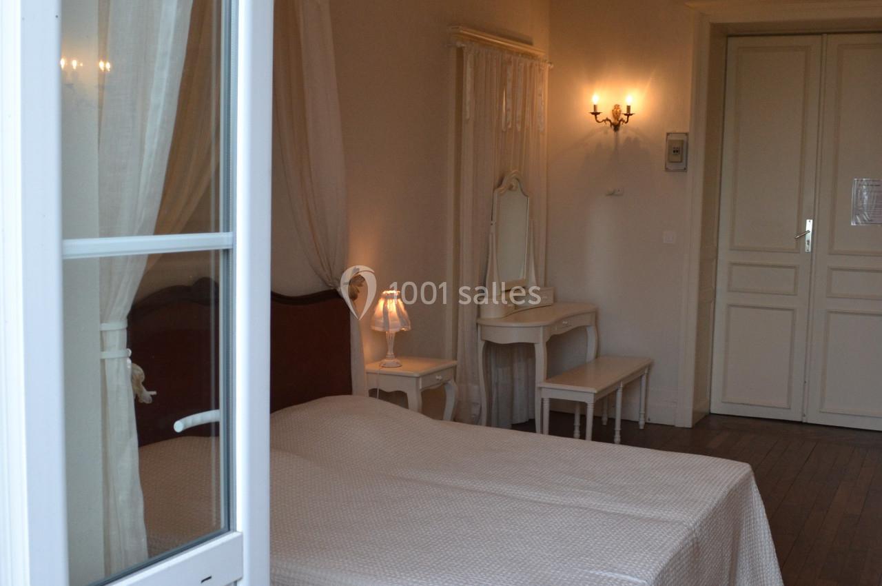 Chambre lumineuse avec lit double, parquet en bois, mobilier blanc et éclairage mural chaleureux.