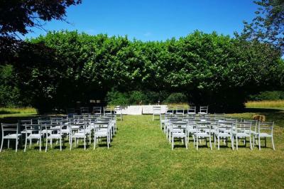 Disposition de bancs en bois face à une arche décorée pour une cérémonie en plein air, entourée de verdure.