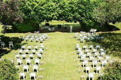 Disposition de bancs en bois face à une arche décorée pour une cérémonie en plein air, entourée de verdure.