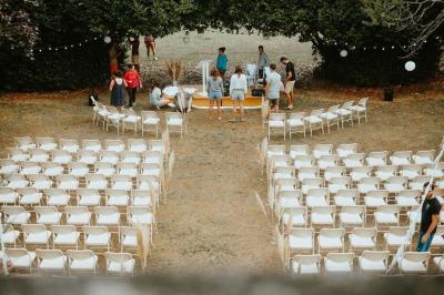 Disposition de bancs en bois face à une arche décorée pour une cérémonie en plein air, entourée de verdure.