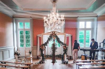 Disposition de bancs en bois face à une arche décorée pour une cérémonie en plein air, entourée de verdure.
