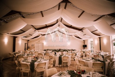 Disposition de bancs en bois face à une arche décorée pour une cérémonie en plein air, entourée de verdure.