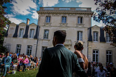 Disposition de bancs en bois face à une arche décorée pour une cérémonie en plein air, entourée de verdure.