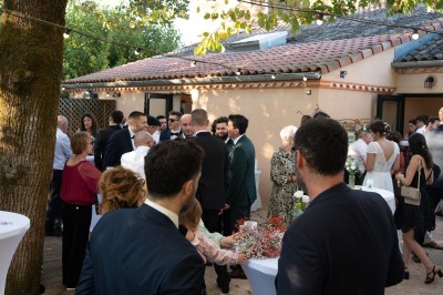 Groupe de personnes discutant sous des guirlandes lumineuses dans un jardin en soirée.