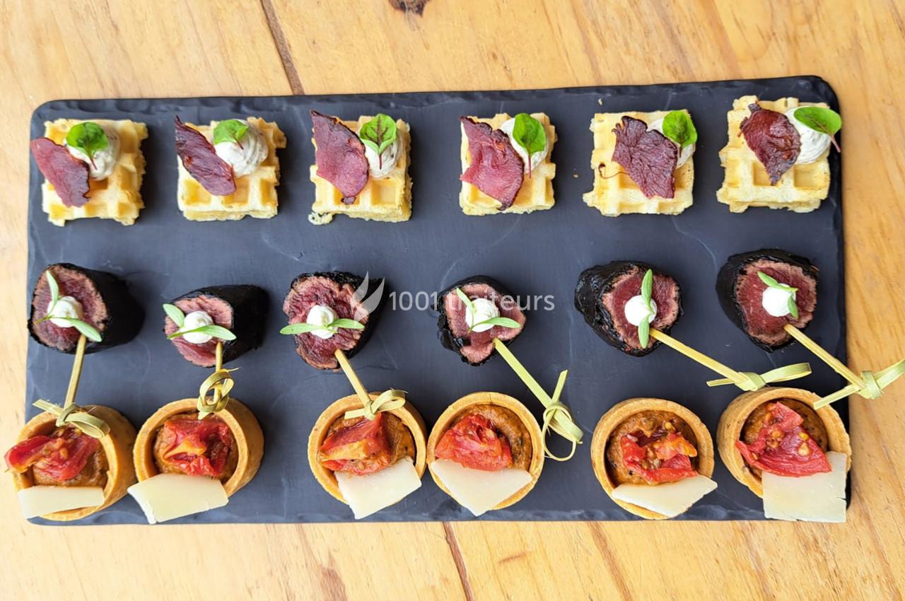 Plateau de bouchées apéritives variées comprenant mini-gaufres, champignons farcis et tartelettes garnies.