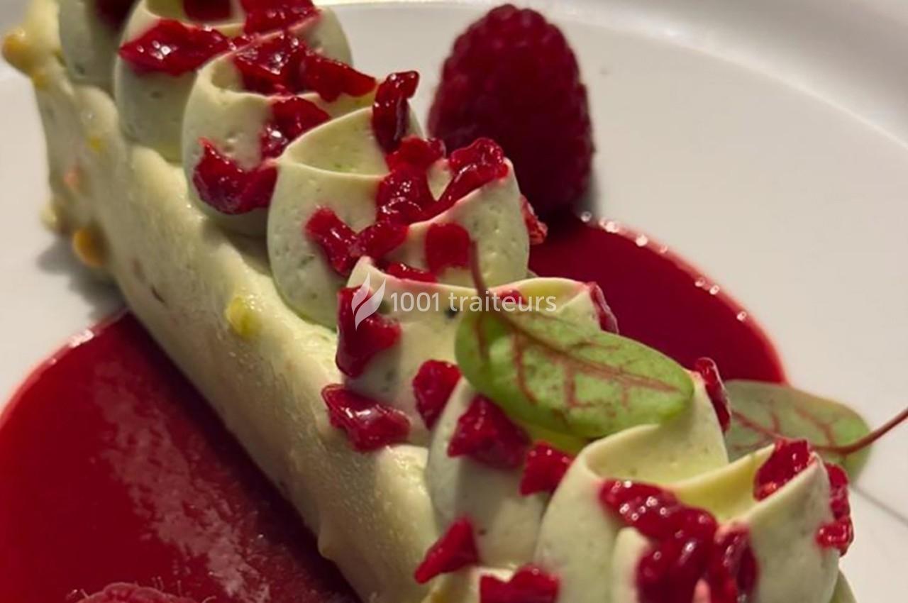 Dessert raffiné composé d'une mousse blanche garnie de morceaux de framboise, sur un coulis rouge, décoré d'une feuille…