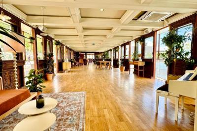 Entrée d'un restaurant aménagé sur un bateau, avec une passerelle en bois et des plantes en pot.