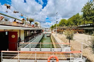Entrée d'un restaurant aménagé sur un bateau, avec une passerelle en bois et des plantes en pot.