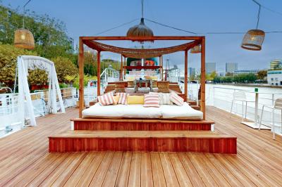 Entrée d'un restaurant aménagé sur un bateau, avec une passerelle en bois et des plantes en pot.