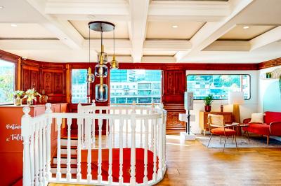 Entrée d'un restaurant aménagé sur un bateau, avec une passerelle en bois et des plantes en pot.