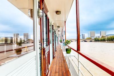 Entrée d'un restaurant aménagé sur un bateau, avec une passerelle en bois et des plantes en pot.