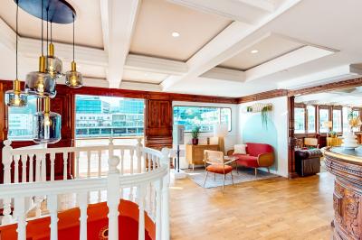 Entrée d'un restaurant aménagé sur un bateau, avec une passerelle en bois et des plantes en pot.