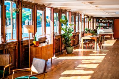 Entrée d'un restaurant aménagé sur un bateau, avec une passerelle en bois et des plantes en pot.