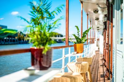 Entrée d'un restaurant aménagé sur un bateau, avec une passerelle en bois et des plantes en pot.