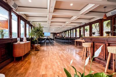 Entrée d'un restaurant aménagé sur un bateau, avec une passerelle en bois et des plantes en pot.