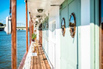 Entrée d'un restaurant aménagé sur un bateau, avec une passerelle en bois et des plantes en pot.