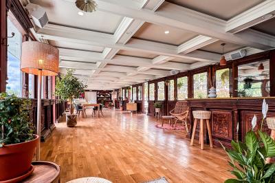 Entrée d'un restaurant aménagé sur un bateau, avec une passerelle en bois et des plantes en pot.