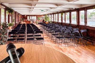 Entrée d'un restaurant aménagé sur un bateau, avec une passerelle en bois et des plantes en pot.