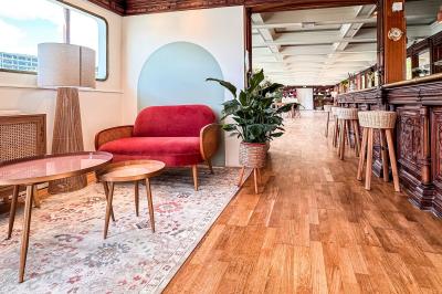 Entrée d'un restaurant aménagé sur un bateau, avec une passerelle en bois et des plantes en pot.