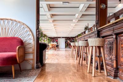 Entrée d'un restaurant aménagé sur un bateau, avec une passerelle en bois et des plantes en pot.
