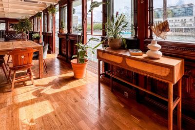 Entrée d'un restaurant aménagé sur un bateau, avec une passerelle en bois et des plantes en pot.