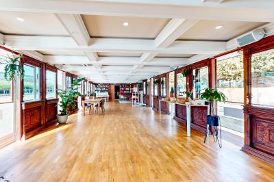 Entrée d'un restaurant aménagé sur un bateau, avec une passerelle en bois et des plantes en pot.