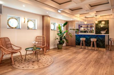 Entrée d'un restaurant aménagé sur un bateau, avec une passerelle en bois et des plantes en pot.